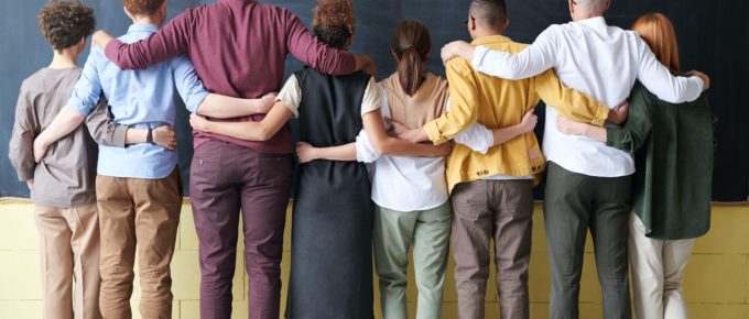 A group standing in front of a chalkboard ready to solve a problem together.