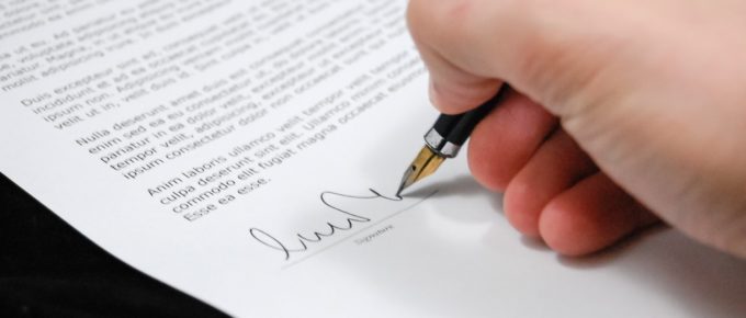 A person signing their name on an agreement.